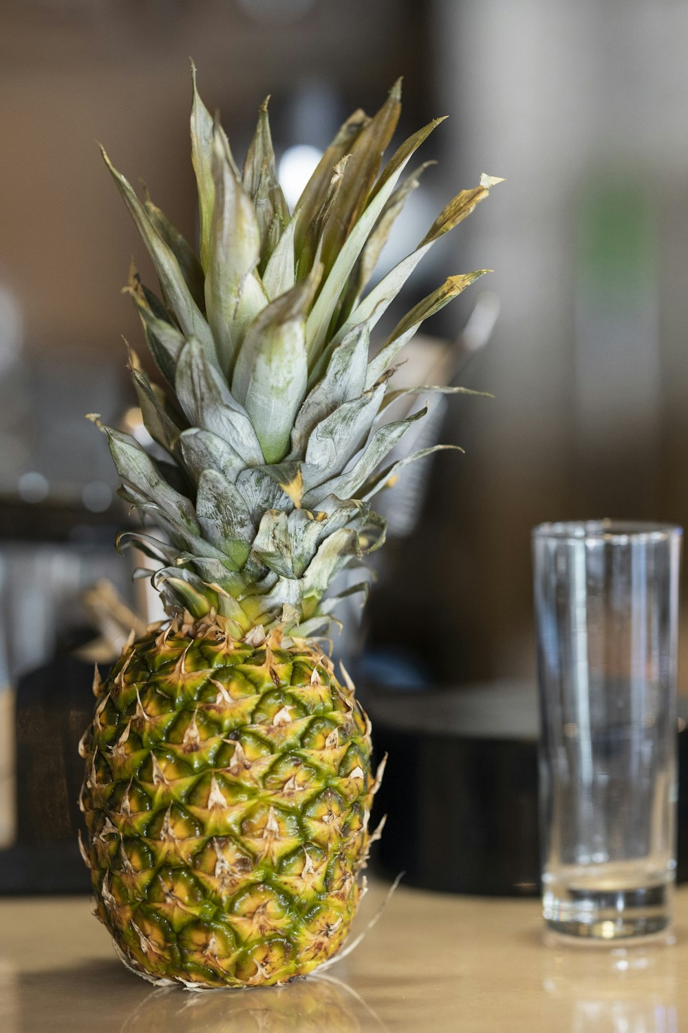 un ananas assis sur une table à côté d’un verre d’eau