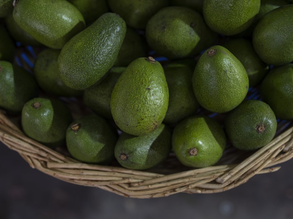 Una canasta llena de fruta verde sentada encima de una mesa