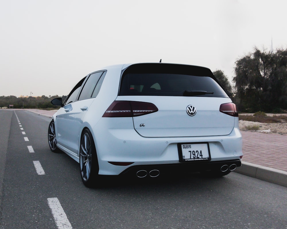 a white car is parked on the side of the road