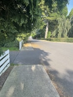 A maintenance worker repairing a fence along a quiet suburban street.