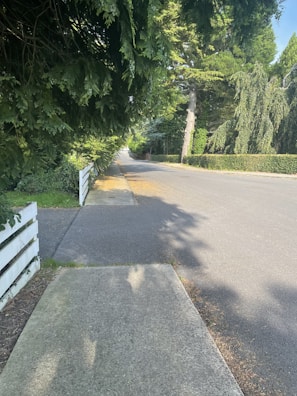 A maintenance worker repairing a fence along a quiet suburban street.
