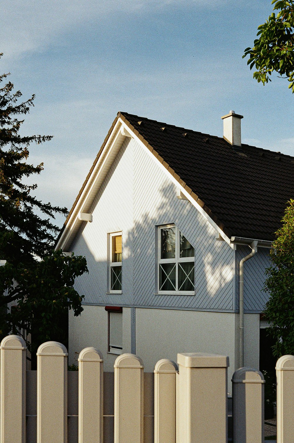 a white house with a black roof and a white picket fence