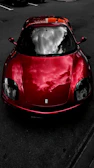 A red sports car reflecting the sky, freshly waxed and shining.