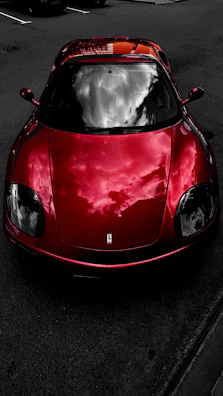 A red sports car reflecting the sky, freshly waxed and shining.