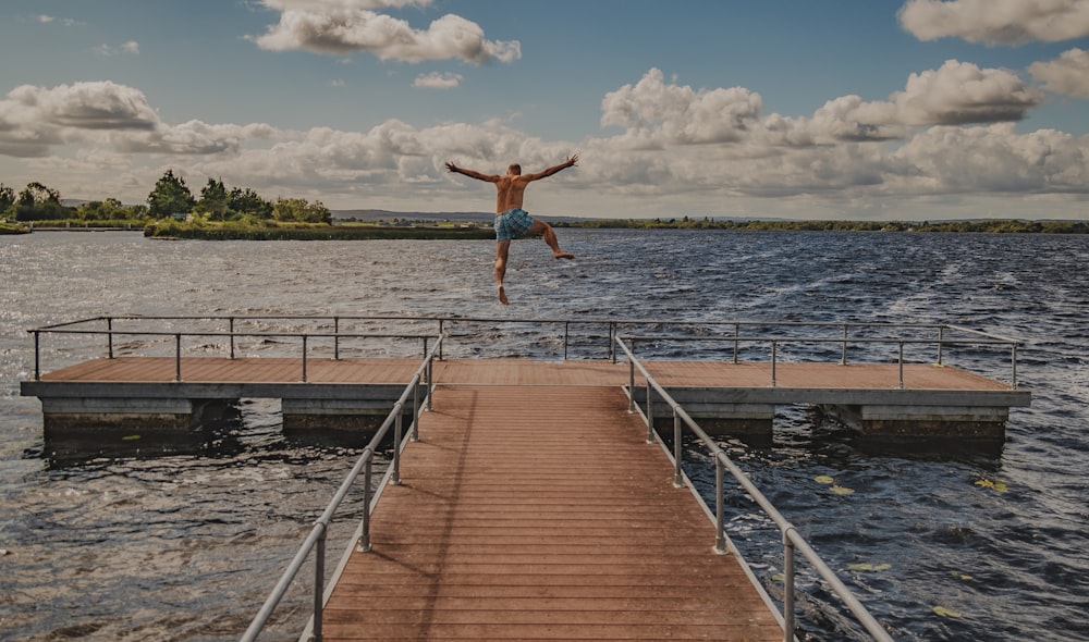 a man jumping off a dock into the water