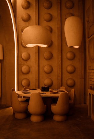 A modern dining room illuminated by a cluster of pasta-inspired lamps in vibrant red and yellow.