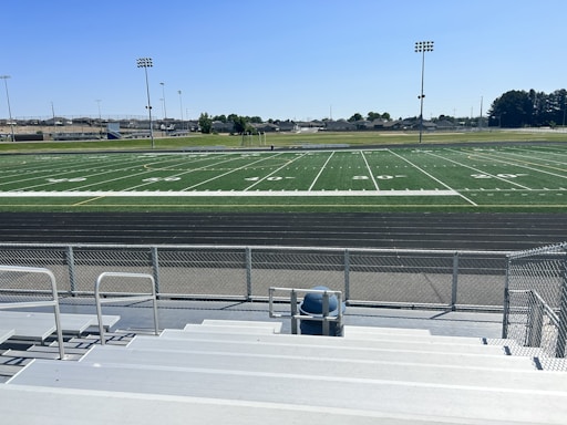 A construction worker measuring a sports field under a bright blue sky.