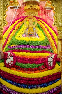 Golden-hued close-up of Sri Sorakayala Swamy idol adorned with fresh marigold garlands and glowing lamps