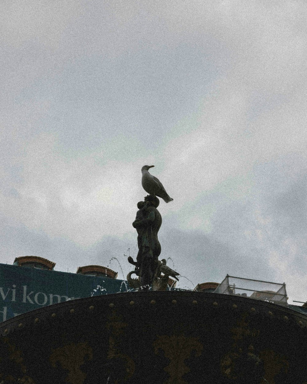 a bird is perched on top of a statue