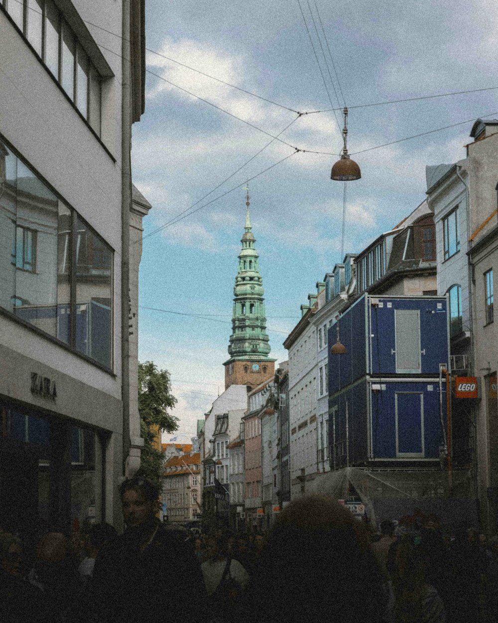 a group of people walking down a street next to tall buildings