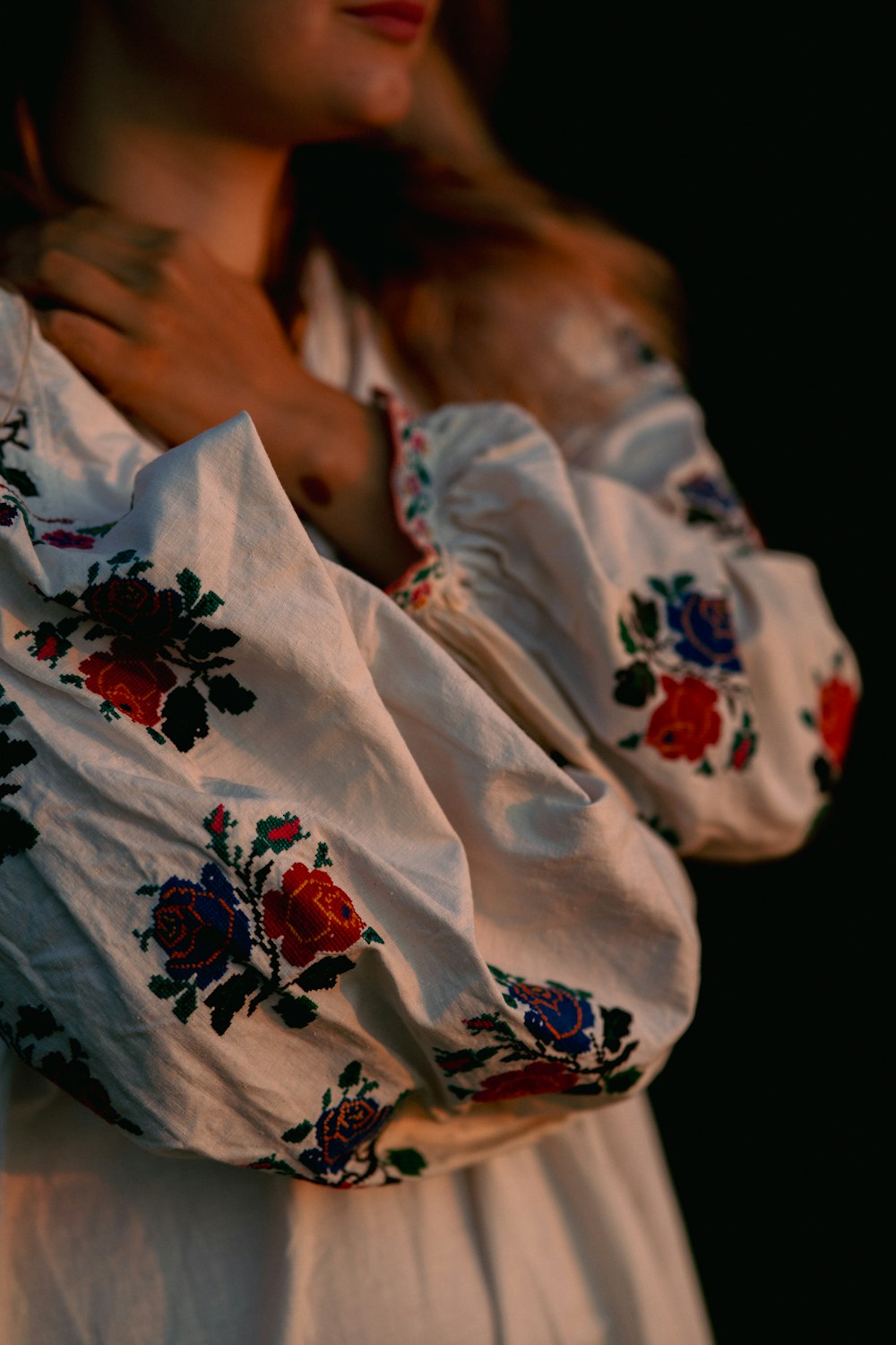 a woman wearing a white dress with red flowers on it