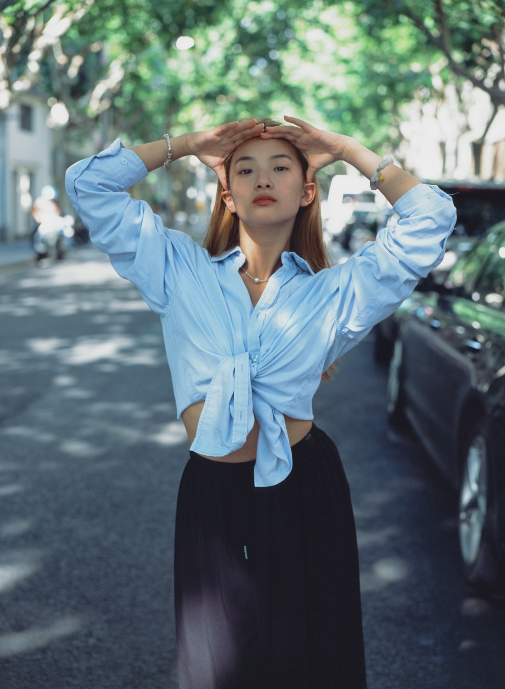 a woman standing on a street with her hands on her head