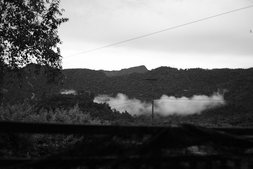 a black and white photo of smoke coming out of a forest