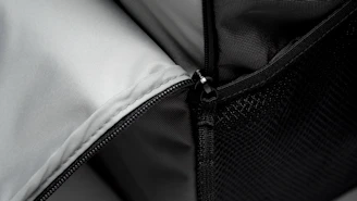 Close-up of a backpack zipper with water droplets on the fabric.