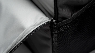 Close-up of a backpack zipper with water droplets on the fabric.