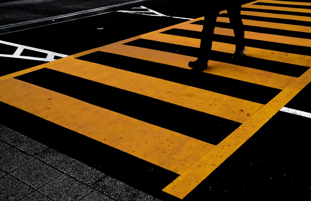 a person walking across a cross walk in the dark