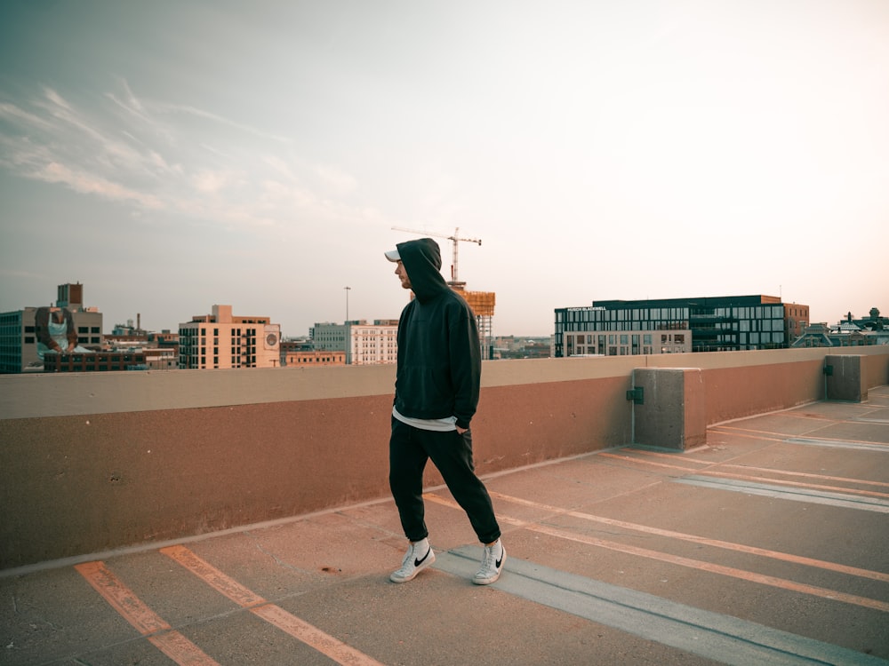 a man walking across a parking lot next to a tall building