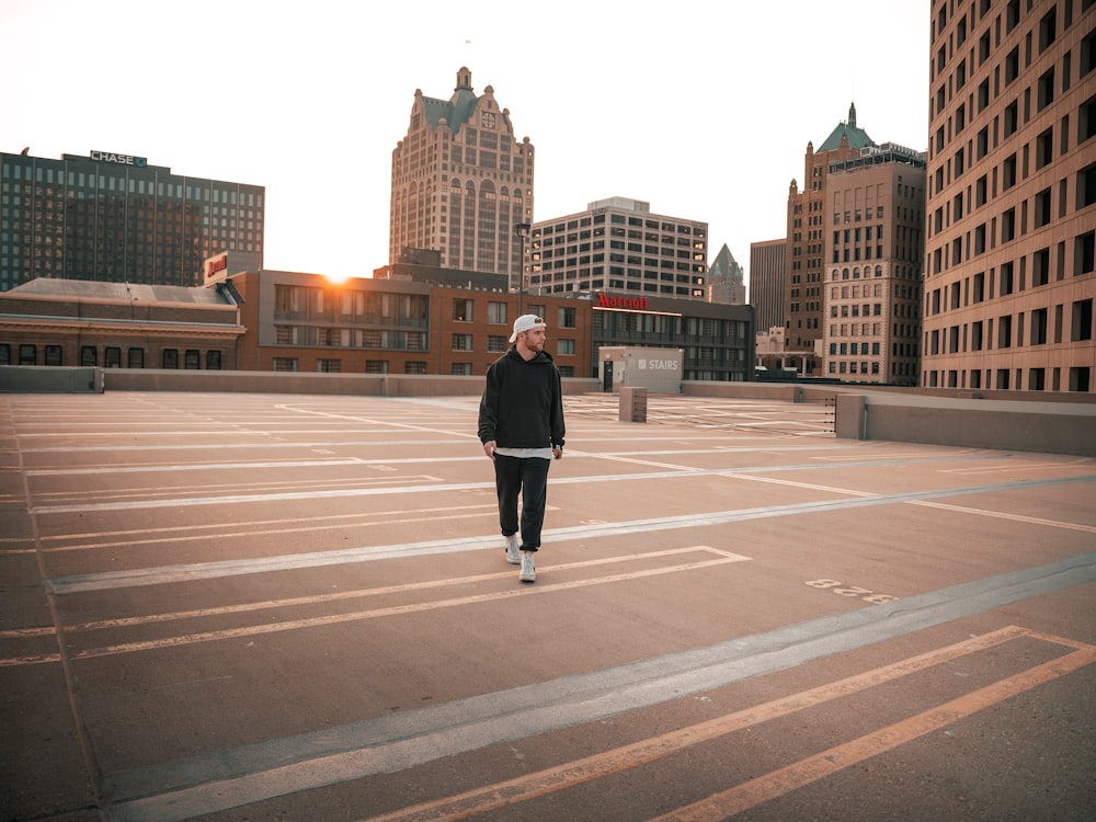 a person standing in a parking lot with buildings in the background