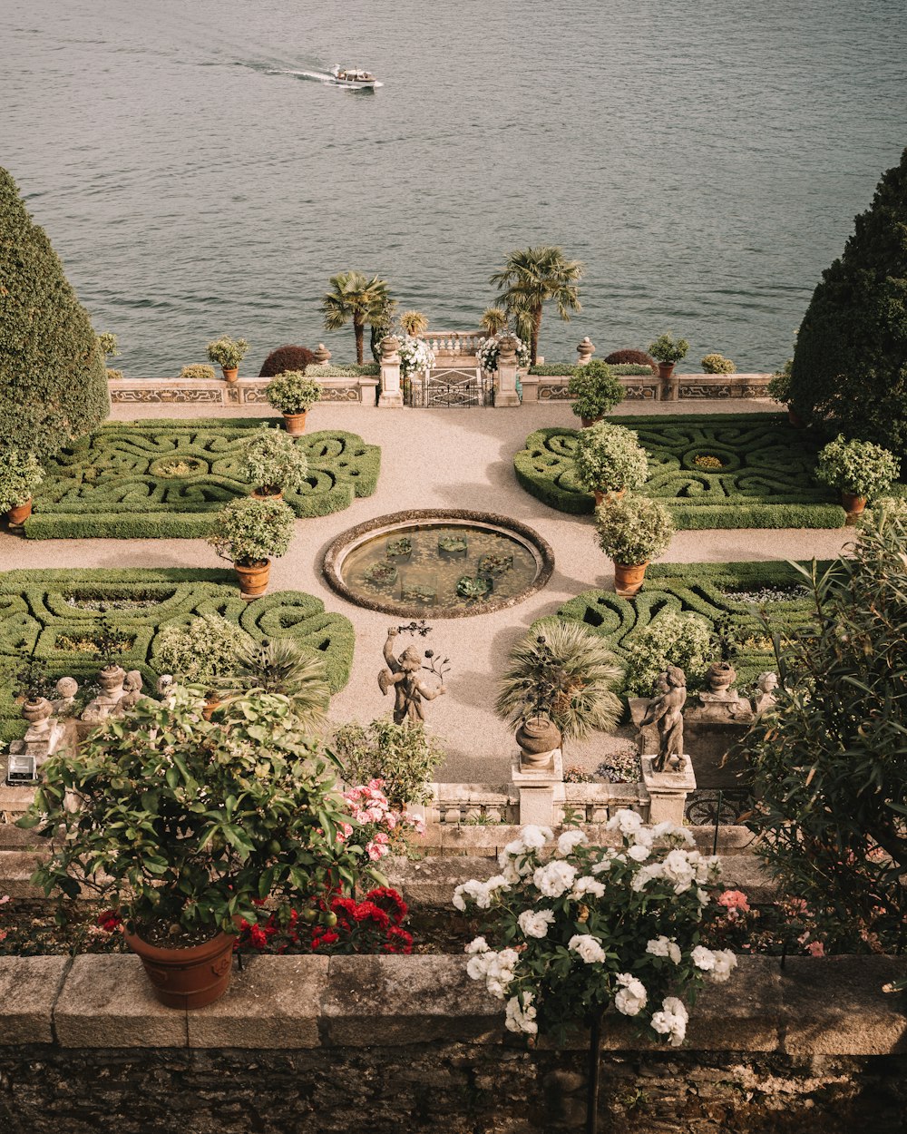 a view of a formal garden with a lake in the background