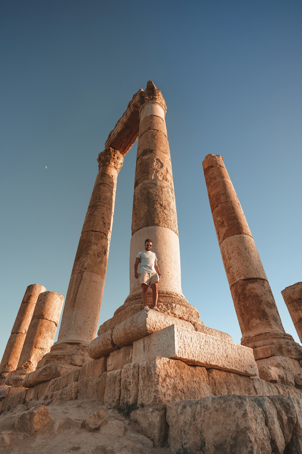 a man sitting on top of a stone pillar