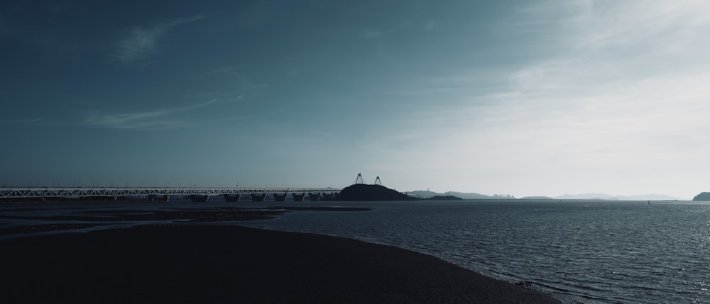 a large body of water with a bridge in the background