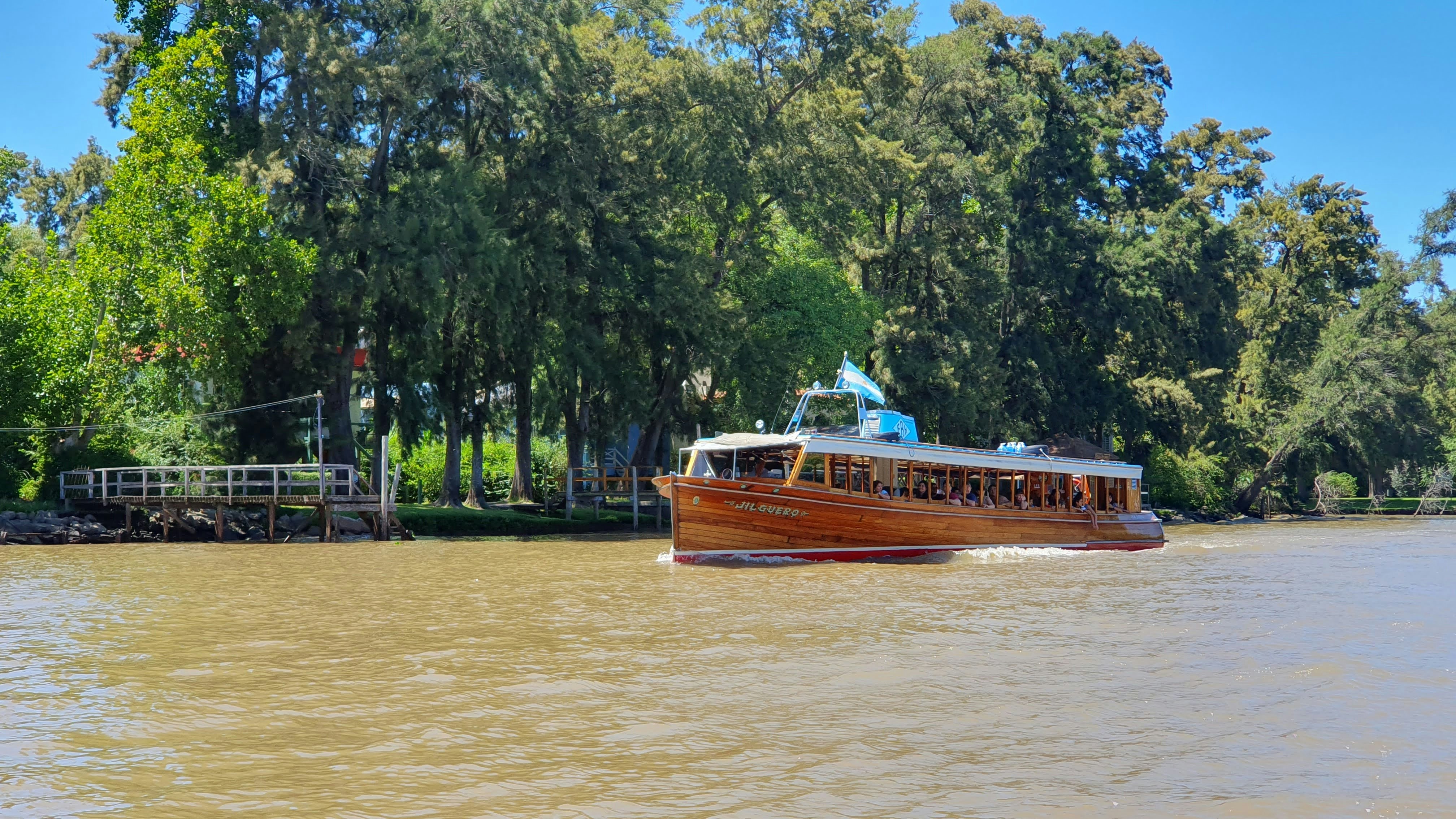 a boat traveling down a river next to a forest