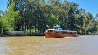 a boat traveling down a river next to a forest
