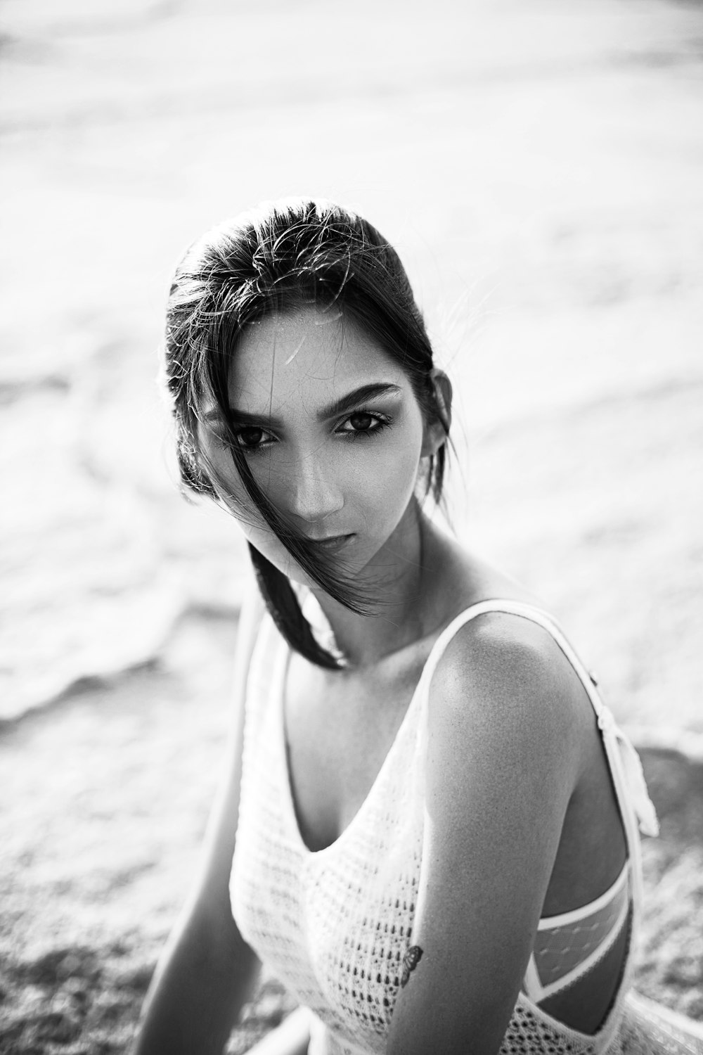 a woman in a white top sitting on the beach