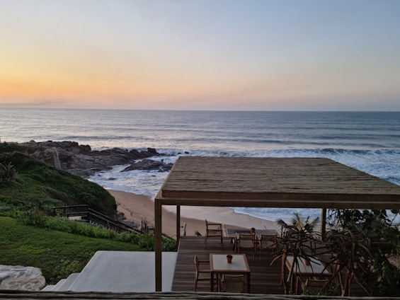 A cozy outdoor terrace with comfortable seating and a view of the sunset over the ocean.