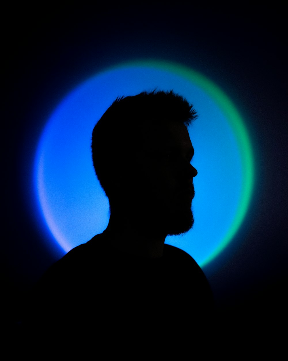 a man standing in front of a blue and green light