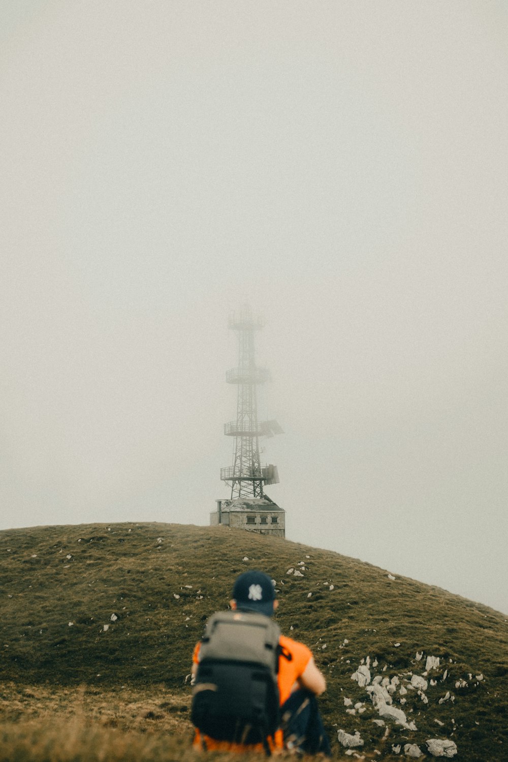 eine person mit einem rucksack, die auf einem hügel sitzt