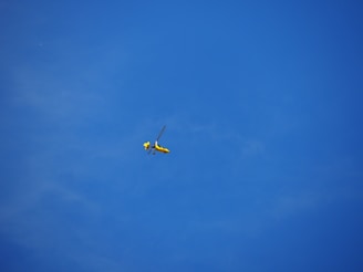 Colorful toy helicopter flying outdoors against a clear blue sky