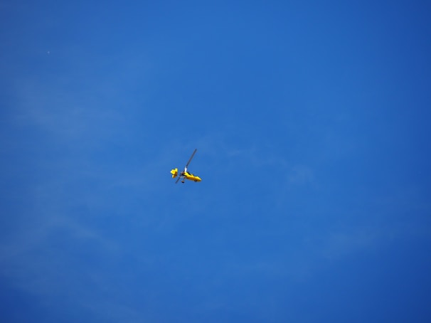 Colorful toy helicopter flying outdoors against a clear blue sky