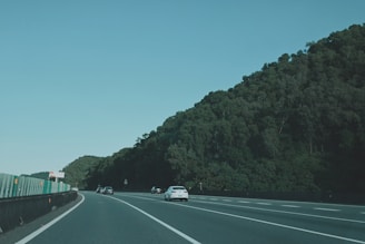 A convoy of cars moving smoothly on a highway under a clear blue sky.