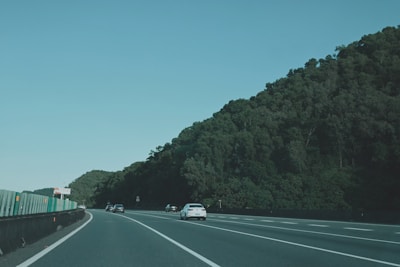A convoy of cars moving smoothly on a highway under a clear blue sky.