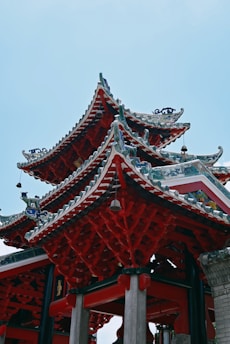 Elaborate temple architecture with ornate, multi-tiered roofs decorated in vibrant red and teal. The intricate details and artistic carvings highlight traditional Asian design influences.