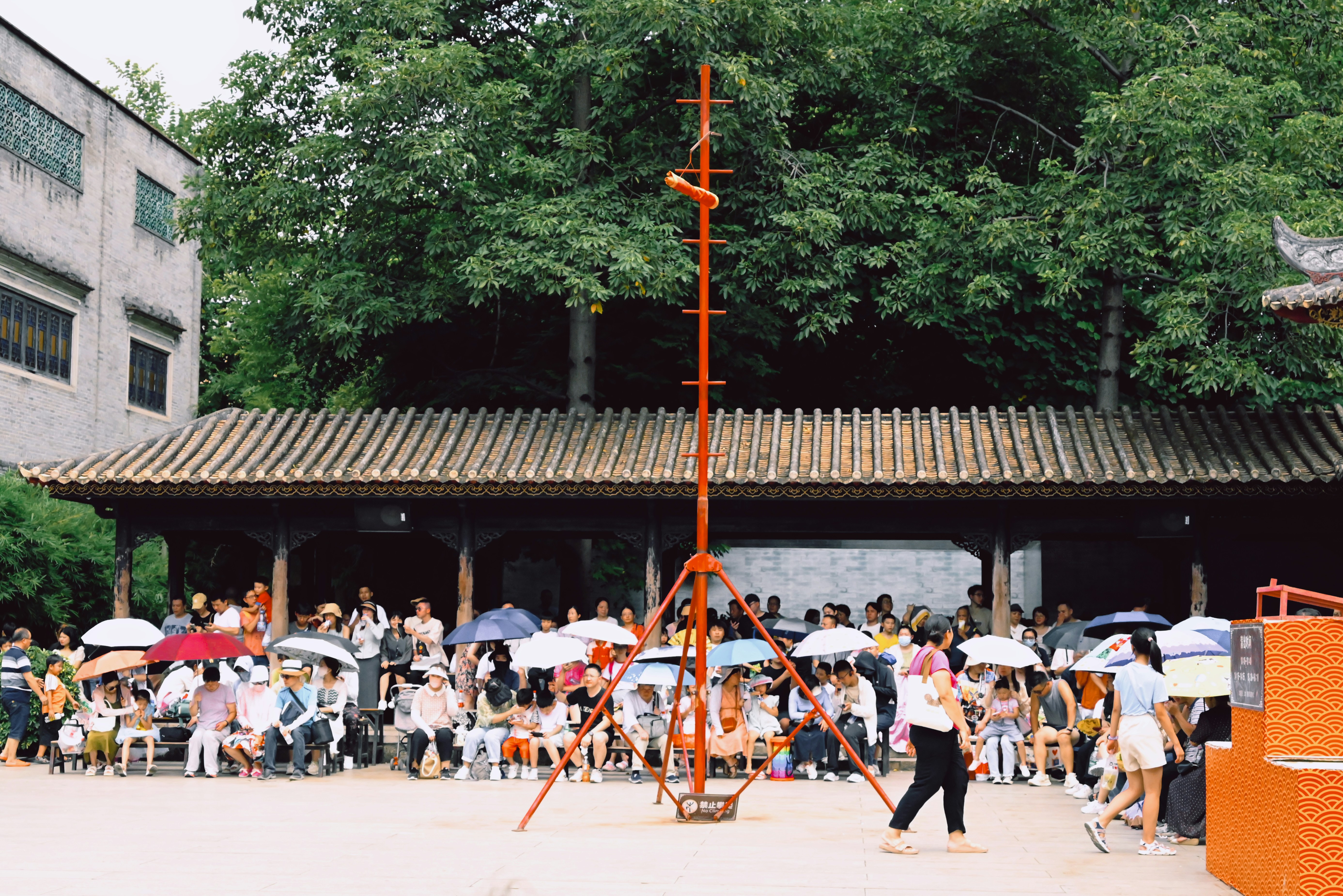 a group of people standing around a building with umbrellas
