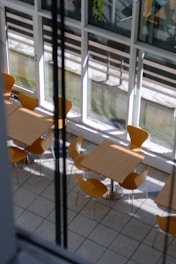 Set of wooden tables arranged neatly in a bright café space.