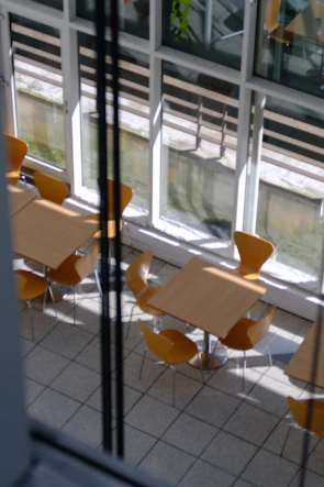 Set of vertical wooden tables arranged by a sunlit window.