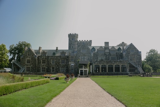 A weathered stone manor house nestled among ancient trees, bathed in soft morning light.