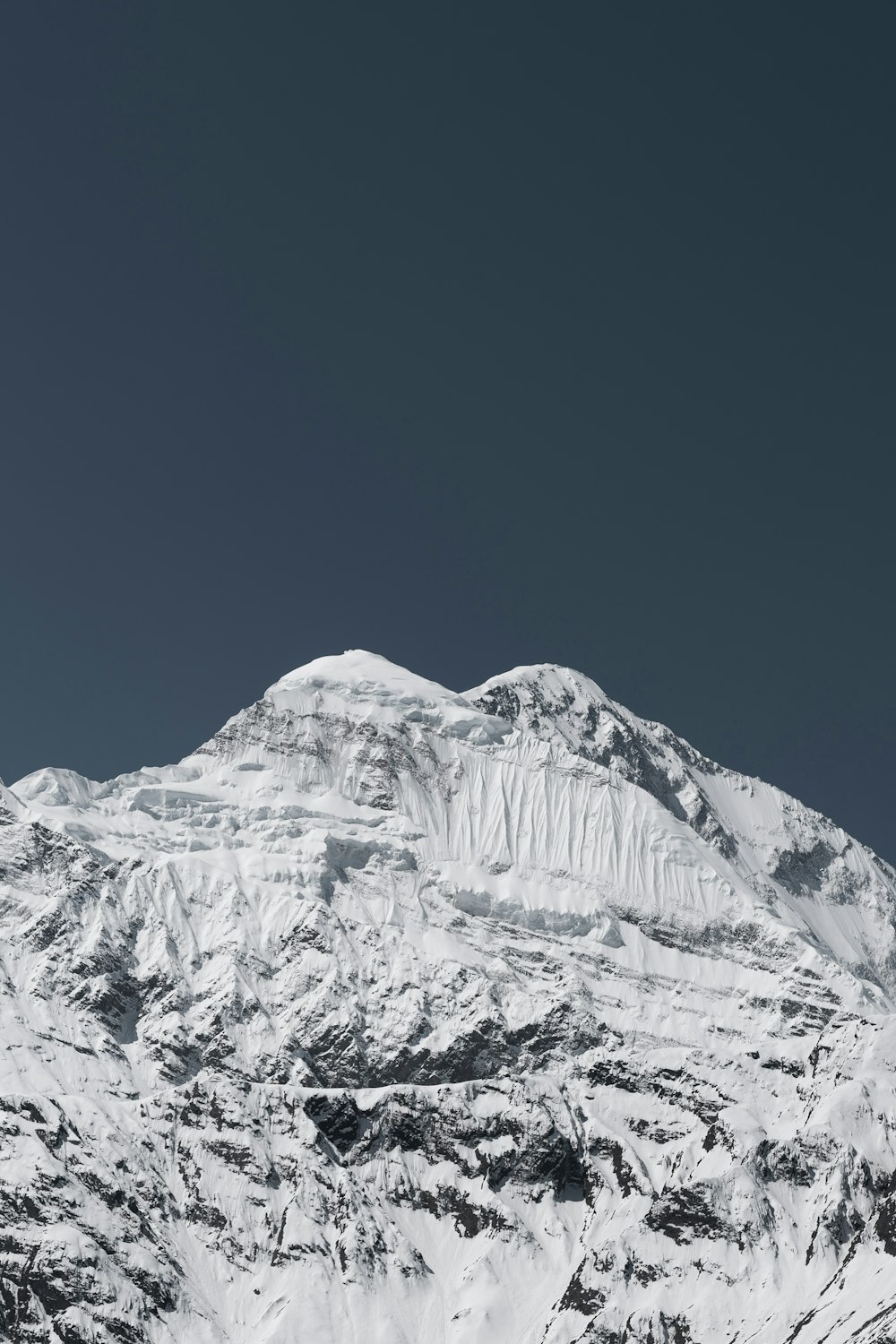 a large mountain covered in snow under a blue sky