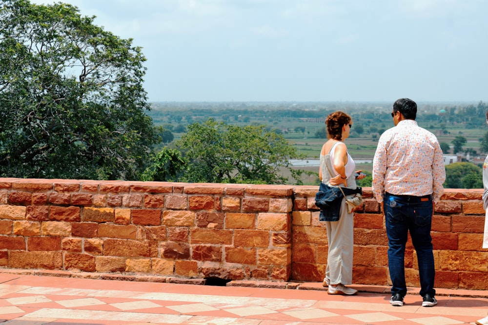 a man and a woman standing on top of a brick wall