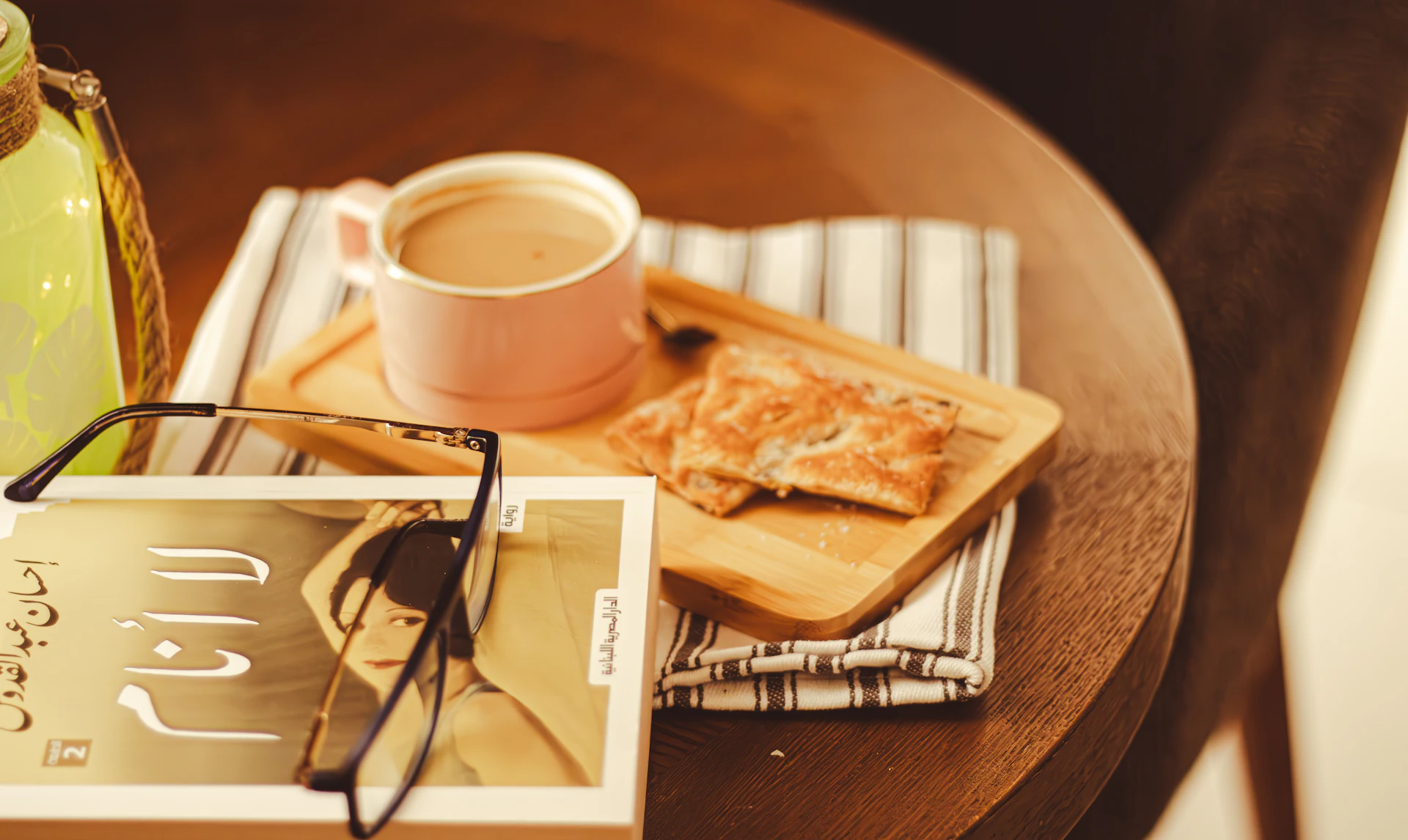 A vibrant display of colorful Moroccan textiles draped over a wooden table, with a steaming cup of coffee and a handwritten notebook resting nearby.