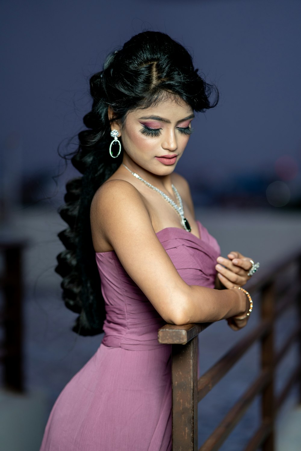 a woman in a purple dress leaning on a rail