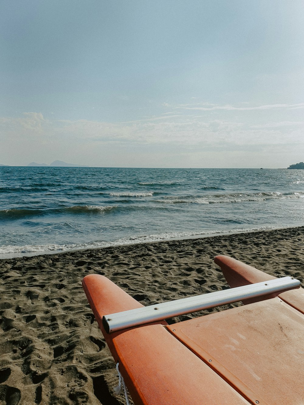 a surfboard laying on the beach next to the ocean