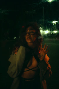 A mysterious evening look featuring a body-harness layered under a tailored blazer in a dimly lit room.