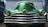 A vintage car with a shiny chrome grille and vibrant green paint. The car's rounded headlights and sleek design suggest a classic automobile aesthetic. It is parked in front of a corrugated metal garage with the shadow of another vehicle visible to the side.