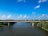 Finished concrete bridge spanning a river with clear blue sky in the background.