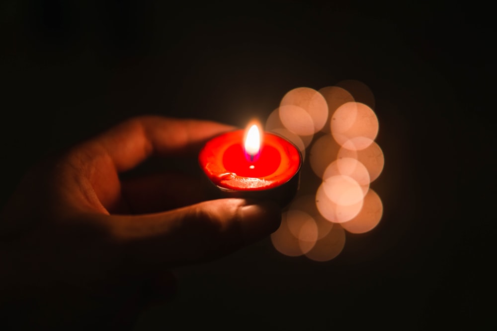 a person holding a lit candle in their hand