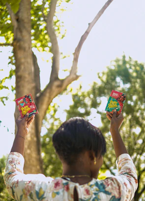 Smiling customer holding a true north nutrition package outdoors with sunlight filtering through trees.